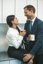 Couple drinking coffee and flirting during lunchtime. Smiling man and woman hold cups of hot drinks looking each other Royalty Free Stock Photo