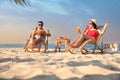 Couple with drinks resting on beach at resort