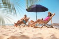 Couple with drinks resting on beach at resort