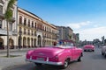 Couple driving by taxi with pink american classic convertible car through streets of Havana, Cuba Royalty Free Stock Photo