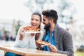 Couple eating pizza outdoors and smiling. Royalty Free Stock Photo