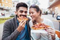 Couple eating pizza outdoors and smiling. Royalty Free Stock Photo