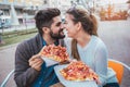 Couple eating pizza outdoors and smiling. Royalty Free Stock Photo