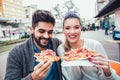 Couple eating pizza outdoors and smiling. Royalty Free Stock Photo