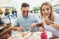 Young couple eating pizza outdoors and smiling.They are sharing pizza in a outdoor cafe Royalty Free Stock Photo