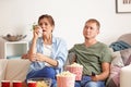 Couple eating popcorn while watching soap opera at home Royalty Free Stock Photo