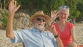 A couple of elderly sitting in chairs at the beach watching the sun and the sea on their summer vacation and they smile and enjoy Royalty Free Stock Photo