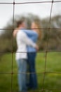 Couple embracing behind a fence