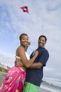 Couple Embracing While Flying Kite On The Beach Royalty Free Stock Photo