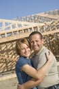 Couple Embracing In Front Of Incomplete House