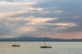 A couple of empty, little sailboat on a lake, beneath a moody sky with sun rays filtering through