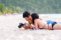 Couple enjoy and happy fun on beach laughing together looking at summer vacation travel photo pictures on retro vintage camera. Ho Royalty Free Stock Photo