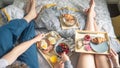 Couple enjoying breakfast in bed with wooden serving trays on bed with food Royalty Free Stock Photo