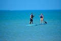 Couple enjoying stand up paddle board on blue sea background 1