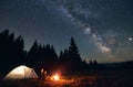 Couple enjoying starry night sky near campfire. Royalty Free Stock Photo