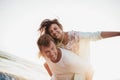 Couple enjoying summer holidays. Handsome young man giving piggyback ride to girlfriend on beach Royalty Free Stock Photo