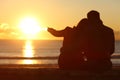 Couple enjoying sunset on the beach in winter Royalty Free Stock Photo