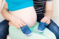 Couple expecting baby, man playing with little shoes Royalty Free Stock Photo