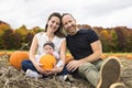 Couple family with daughter on a field with pumpkins