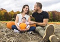 Couple family with daughter on a field with pumpkins