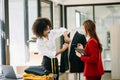 Couple of fashion designers working with fabric and clothing sketches at the studio full of tailoring tools and holds tablet and Royalty Free Stock Photo