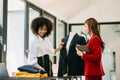 Couple of fashion designers working with fabric and clothing sketches at the studio full of tailoring tools and holds tablet and Royalty Free Stock Photo