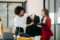 Couple of fashion designers working with fabric and clothing sketches at the studio full of tailoring tools and holds tablet and Royalty Free Stock Photo