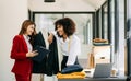 Couple of fashion designers working with fabric and clothing sketches at the studio full of tailoring tools and holds tablet and Royalty Free Stock Photo