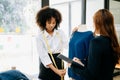 Couple of fashion designers working with fabric and clothing sketches at the studio full of tailoring tools and holds tablet and Royalty Free Stock Photo