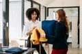 Couple of fashion designers working with fabric and clothing sketches at the studio full of tailoring tools and holds tablet and Royalty Free Stock Photo