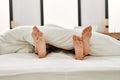 Couple feet under sheets on the bed at home Royalty Free Stock Photo