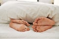 Couple feet under sheets on the bed at home Royalty Free Stock Photo