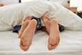 Couple feet under sheets on the bed at home Royalty Free Stock Photo