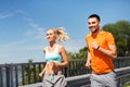 Couple with fitness trackers running along bridge