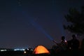 Couple with flashlights near camping tent outdoors at night