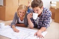 Couple, floor plan and blueprints with moving boxes for renovation, new home or property investment. Man, woman and Royalty Free Stock Photo