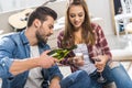 Young attractive couple sitting on floor at home and pouring champagne Royalty Free Stock Photo