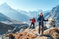 Couple following Everest Base Camp trekking route near Dughla 4620m. Backpackers carrying Backpacks and using trekking poles and