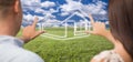 Couple Framing Hands Around House Figure in Grass Field