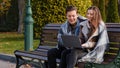 Couple freelancers two partners people young caucasian woman and man entrepreneurs sit on bench in park use urban wifi Royalty Free Stock Photo