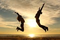 Couple or friends jumping on the beach at sunset Royalty Free Stock Photo