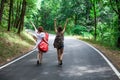 Couple of friends in a road hitchhiking with backpack and guitar