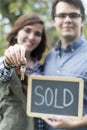 Couple in front of new home holding sold blackboard sign and keys Royalty Free Stock Photo