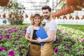 Couple of gardeners holding clipboards by flowers