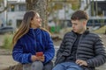 Couple of girl and boy sitting on the bench in a public park Royalty Free Stock Photo