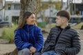 Couple of girl and boy sitting on the bench in a public park Royalty Free Stock Photo