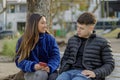 Couple of girl and boy sitting on the bench in a public park Royalty Free Stock Photo