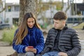 Couple of girl and boy sitting on the bench in a public park Royalty Free Stock Photo
