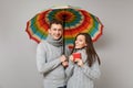 Couple girl guy in gray sweaters scarves together under umbrella isolated on grey wall background, studio portrait Royalty Free Stock Photo