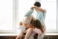 Couple girl and guy play with pillows near window. Royalty Free Stock Photo